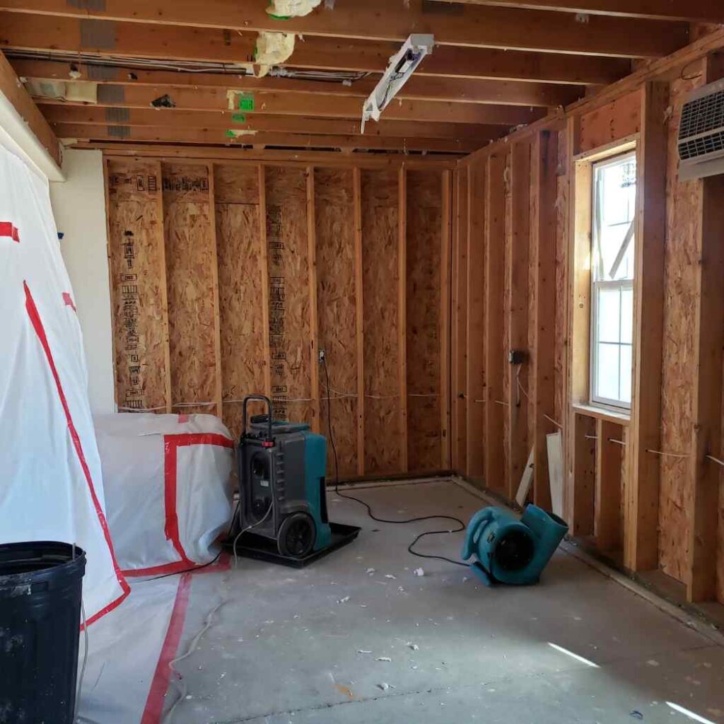 Room under renovation with exposed wooden framing and ventilation fans.