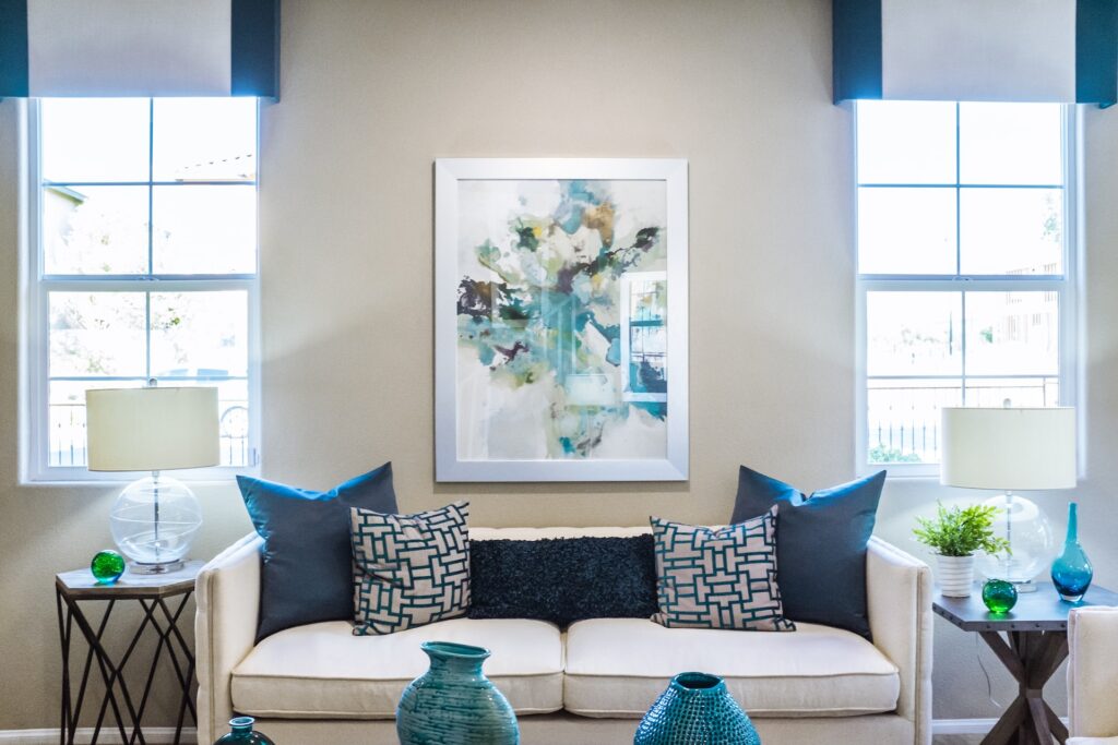 Elegant beige sofa with patterned pillows and blue accents in a bright living room.